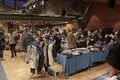 Blick in eine Halle, viele Flohmarktstände sind aufgebaut und Besucher schauen die Waren an